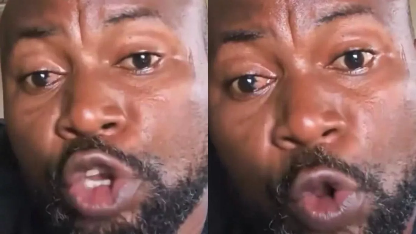 A stressed man looking at his phone while sitting at a coffee table