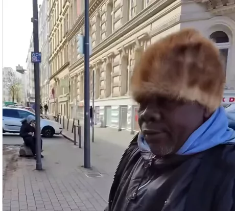 A tired-looking man sitting on a sidewalk in Hamburg