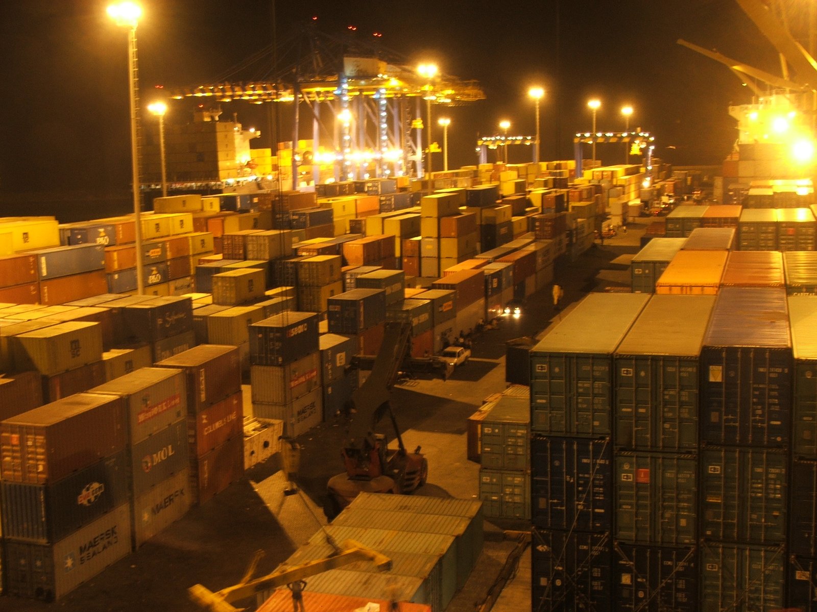 A wide shot of a busy shipping port in Ghana with cargo containers