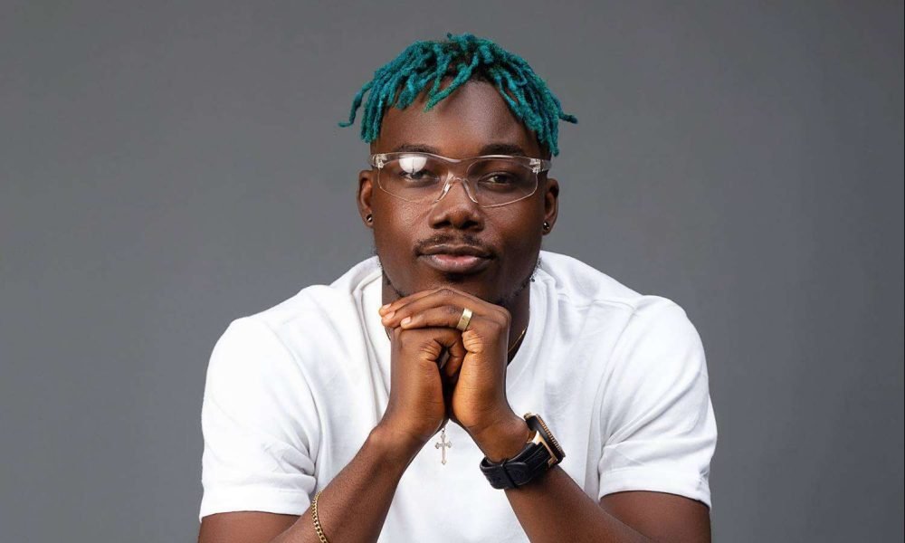 Camidoh smiling while holding a microphone during a studio session