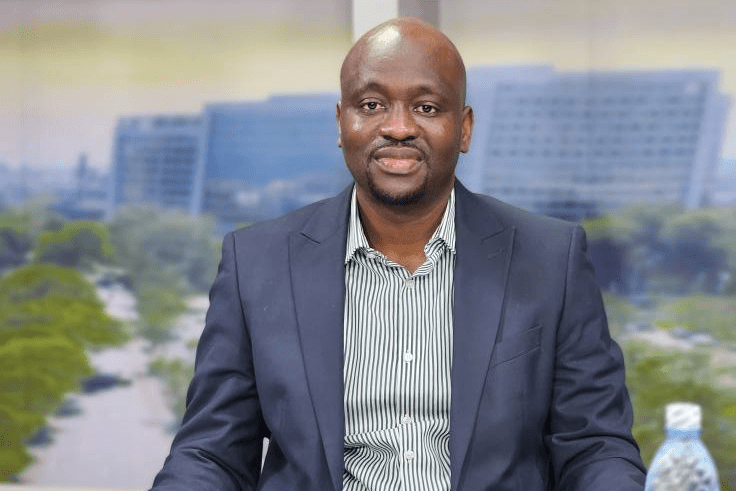 A busy local market with shoppers checking fresh produce prices