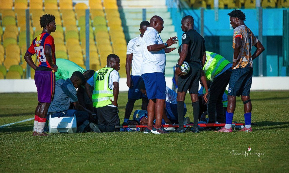 A goalkeeper lying on a stretcher while medical staff attend to him on the field